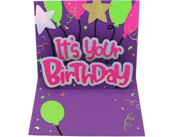 May include: A pop-up birthday card with a purple background, featuring the text "It's Your Birthday" in pink and blue. The card is decorated with balloons and stars in various colors, including green, pink, and gold. Confetti and swirls add to the festive design.