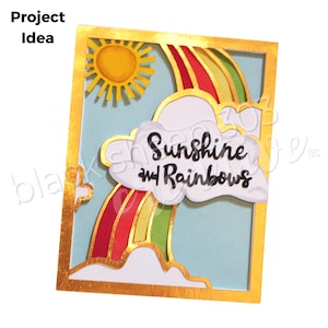 Può includere: Un biglietto con cornice dorata e sfondo blu che presenta un sole giallo, un arcobaleno e nuvole bianche. Il testo "Sunshine and Rainbows" è scritto in nero su una nuvola bianca.