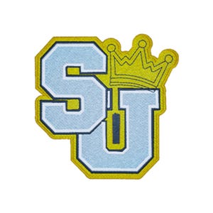 May include: An embroidered patch featuring the letters S and U in light blue with dark blue outlines. A yellow crown sits atop the letter U. The entire design is bordered by a thick yellow stitched edge, creating a bold, collegiate-style emblem.