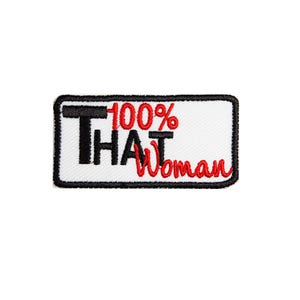 May include: Embroidered patch with the text "THAT Woman" in black and red. The patch is rectangular with a white background and a black border. The words "100%" are above "THAT".
