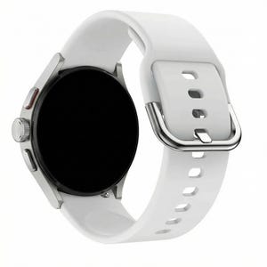May include: A silver smartwatch with a black screen and a white silicone band. The band features a silver buckle and multiple adjustment holes. The watch has a round face with a silver bezel and a red accent button.