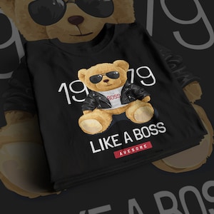 May include: Black t-shirt with a brown teddy bear wearing sunglasses and a leather jacket. The teddy bear is sitting with the text "1979" and "LIKE A BOSS" printed on the shirt. The text "AWESOME" is printed in red below the text "LIKE A BOSS".