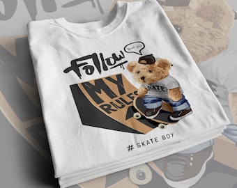May include: White t-shirt with a graphic of a teddy bear skateboarding on a ramp. The graphic says "Follow My Rules" and "#Skate Boy". The teddy bear is wearing a blue and white striped shirt, blue jeans, and a black cap. The teddy bear is holding a skateboard with the word "Skate" on it.
