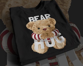 May include: Black t-shirt with white text that says "BEAR HUG" and a cartoon brown teddy bear wearing a red and white striped scarf.