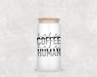 Op de afbeelding: Een witte tumbler met een zwart-wit ontwerp met de tekst "half coffee half human". De tumbler heeft een houten deksel en een rietje.