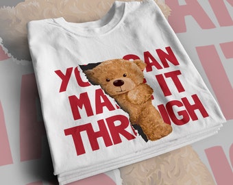 May include: White t-shirt with a red graphic that says "You Can Make It Through" with a brown teddy bear peeking out from behind the text.