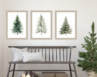 May include: Three framed watercolor paintings of evergreen trees on a white wall above a black wooden bench. The bench has a white and black patterned pillow on it. There is a small potted Christmas tree to the right of the bench.