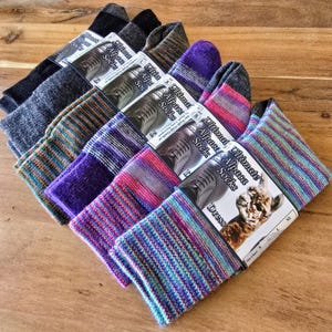 May include: A stack of six pairs of colorful alpaca socks with striped patterns. The socks are labeled "Ultimate Alpaca Socks" and "Dress".