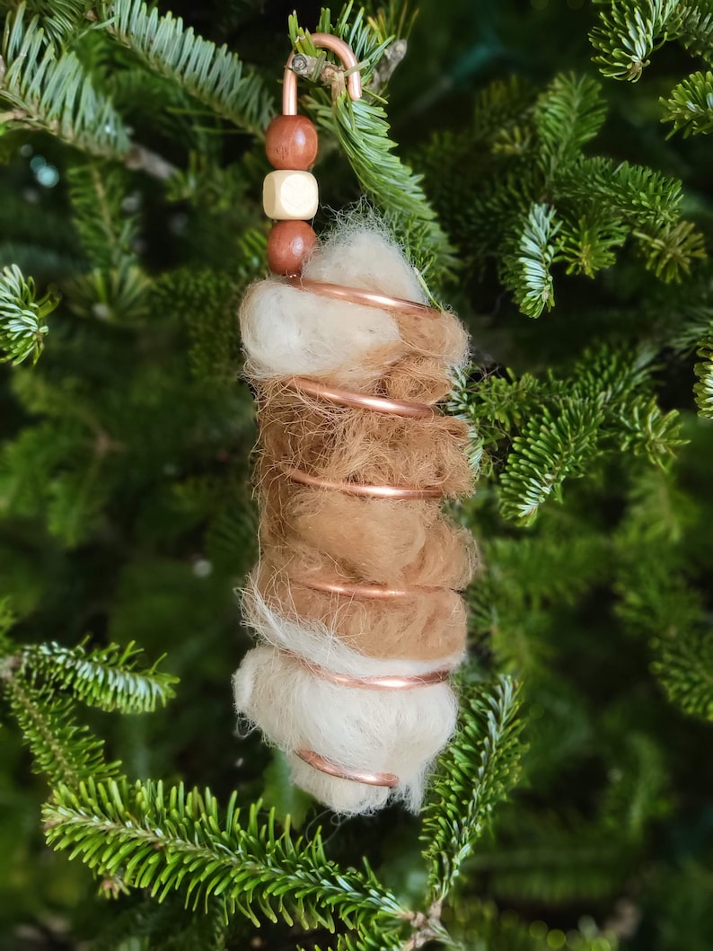 May include: A handmade Christmas ornament featuring a spiral of copper wire wrapped with white and brown wool felt. The ornament is adorned with wooden beads in shades of brown and gold.