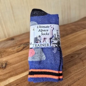 May include: Blue and grey alpaca socks with an orange and black stripe at the top. The socks have a label that says "Ultimate Alpaca Socks" and features a picture of an alpaca. The label also says "Trainer" and "Size XL".