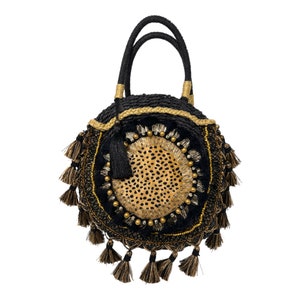 May include: A round black and gold straw bag with a leopard print design and tassels.
