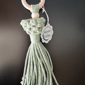 May include: A light green crocheted baby teether with a wooden ring and a tag that says "Moon + Vines".