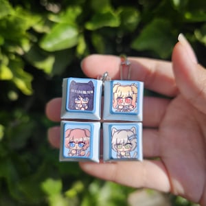 K&ouml;nnte beinhalten: Vier blaue und wei&szlig;e Keycaps mit Anime-Illustrationen von M&auml;dchen. Jede Keycap zeigt ein anderes M&auml;dchen mit einzigartigen Haaren und Kleidung.