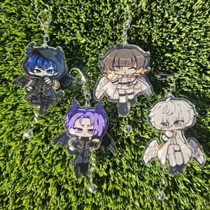 May include: Four anime-style character charms with wings. The charms are on chains with silver bells. The characters are a purple-haired demon, a blue-haired demon, a white-haired angel, and a brown-haired angel.