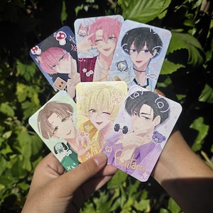 May include: A collection of six rectangular trading cards featuring anime-style illustrations of characters with various hair colors including pink, black, and blonde. Each card displays decorative stickers like mushrooms, animals, and the name Rintaro.