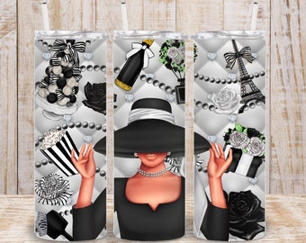 May include: A black and white tumbler design featuring a woman wearing a black hat and dress, with Parisian-themed elements like the Eiffel Tower, a hot air balloon, and a bottle of champagne.