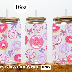 Op de afbeelding: Drie 473 ml glazen blikverpakkingen met een donut- en strikpatroon. De middelste verpakking heeft de tekst "Donut Worry" in roze met een roze donut-afbeelding.