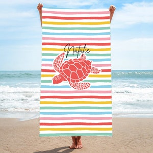 May include: A colorful beach towel with a red sea turtle and the name Natalie printed on it. The towel has rainbow stripes.