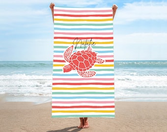 May include: A colourful beach towel with a red sea turtle and the name Natalie printed on it. The towel has rainbow stripes.