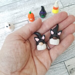 Op de afbeelding: Twee zwarte en witte dwerg ornamenten met zwarte kattenoren en maskers. De dwergen hebben witte baarden en bruine neuzen.