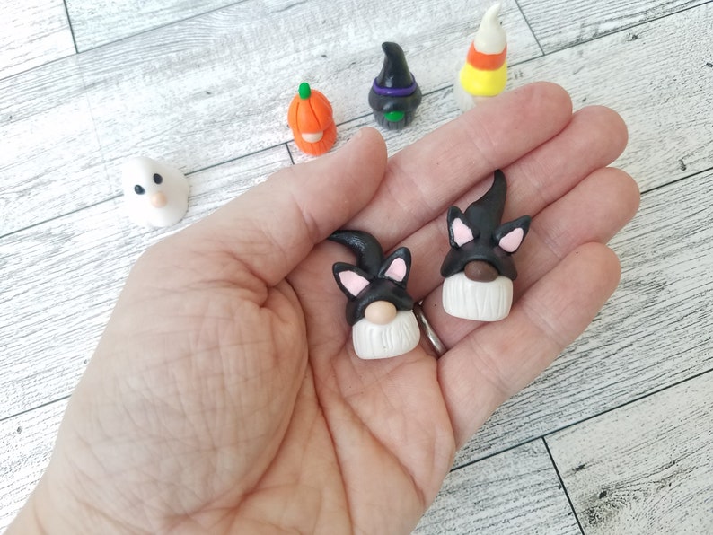 Op de afbeelding: Twee zwarte en witte dwerg ornamenten met zwarte kattenoren en maskers. De dwergen hebben witte baarden en bruine neuzen.