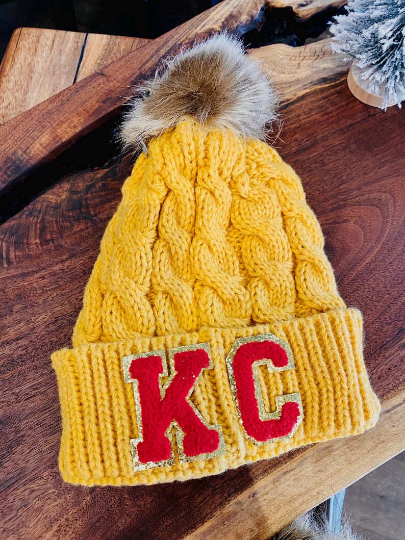 Kansas City Chiefs inspired cable knit Beanie in golden yellow with red KC Chenille Patch Letters on the folded cap line.