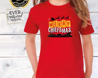 May include: Red t-shirt with a graphic of a Santa Claus pulling a sleigh with reindeer and the text "Merry Chiefmas" in yellow boxes.