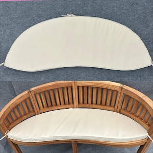 May include: A semi-circular, off-white cushion with thin fabric ties at the corners. The cushion is shown both separately and placed on a curved, slatted wooden bench with a natural brown finish and a rounded backrest design.