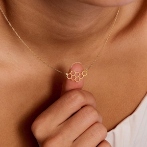 May include: A gold necklace with a honeycomb pendant. The pendant is made of a delicate, openwork design.