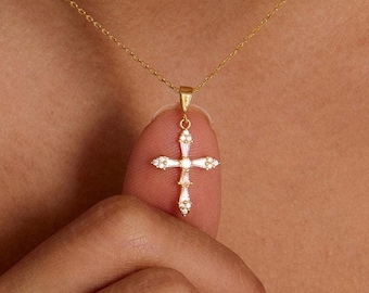 May include: A gold chain necklace with a small, diamond-encrusted cross pendant.