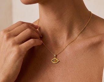 May include: A gold-toned necklace featuring a delicate chain and an eye-shaped pendant. The pendant has a textured gold border and a central, smooth, brown and black striped tiger's eye gemstone inlay, creating a distinct, symmetrical, almond-like shape.