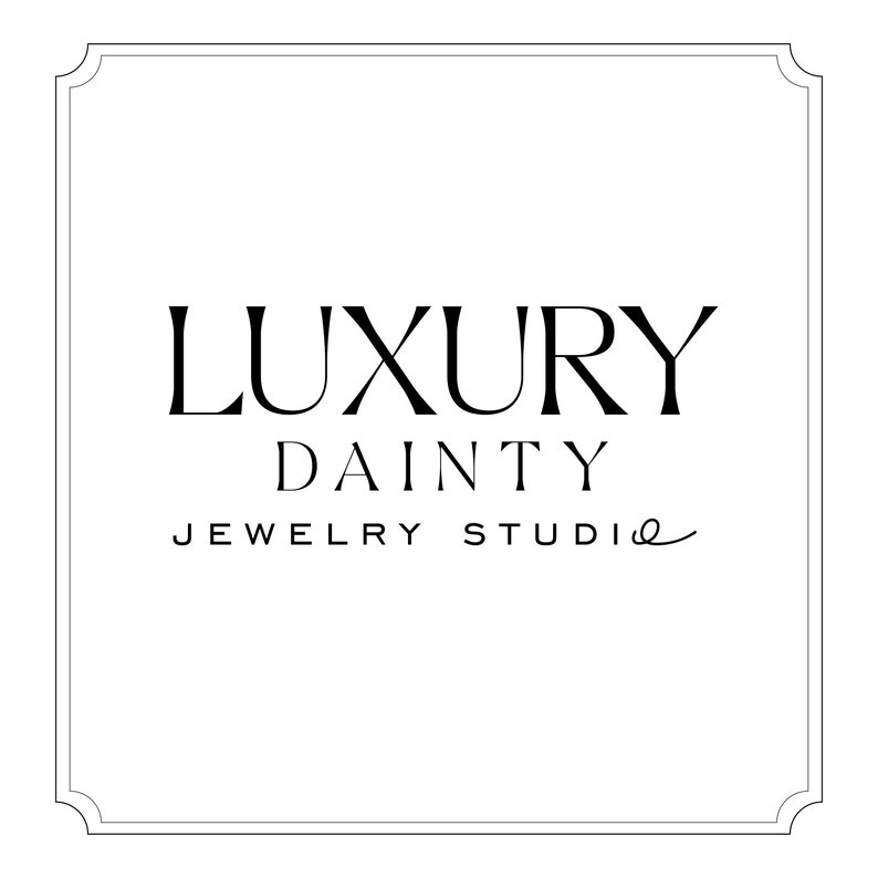 K&ouml;nnte beinhalten: Ein quadratisches, wei&szlig;es Grafikdesign mit dekorativem Rahmen. Der Text "LUXURY DAINTY JEWELRY STUDIO" ist in eleganter schwarzer Schrift dargestellt. Das Design deutet auf eine hochwertige Schmuckmarke hin.