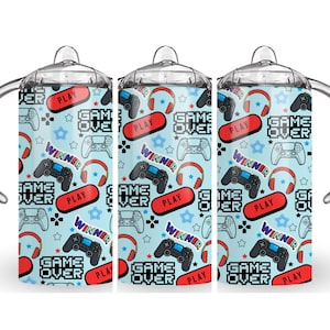 May include: Three clear plastic tumblers with lids and handles. Each tumbler features a blue background with a repeating pattern of video game controllers, headphones, and the words "Game Over", "Play", and "Winner".
