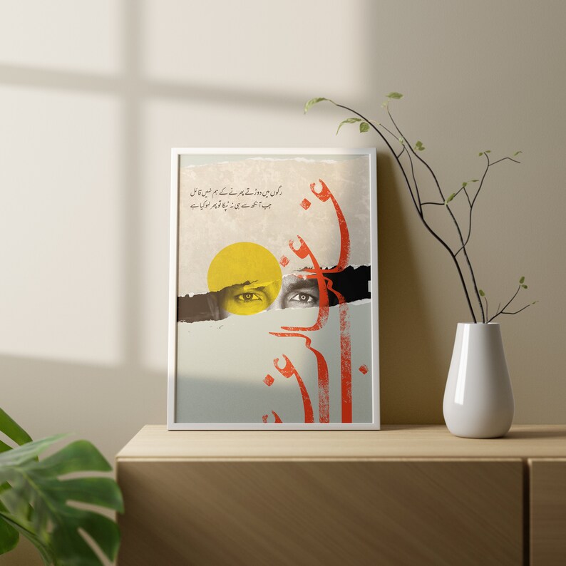 May include: Framed art print with Urdu script in red and a yellow sun shape. The artwork features a torn paper effect revealing a pair of eyes. The print is displayed on a wooden surface. The text in the image is in Urdu.
