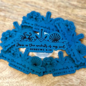 May include: A collection of teal stickers with a nautical theme. Each sticker features an anchor, crab, and seashell design, along with the text "Jesus is the anchor of my soul" and the reference "Hebrews 6:19".