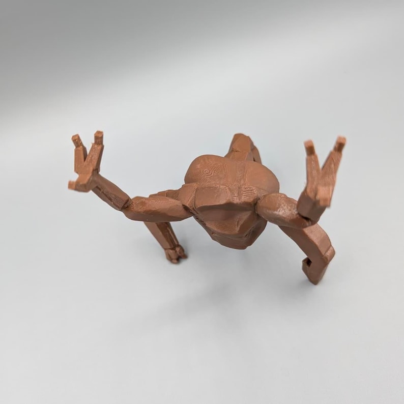 May include: A brown, articulated figure in a crawling pose, with arms and legs extended. The figure has a geometric, blocky design, with visible joints. The figure is positioned against a plain, light background.