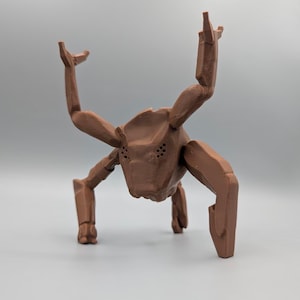 May include: A brown, geometric sculpture of a creature with multiple limbs and a head with several small holes. The sculpture has a stylized, angular design and is posed as if it is walking or crawling.
