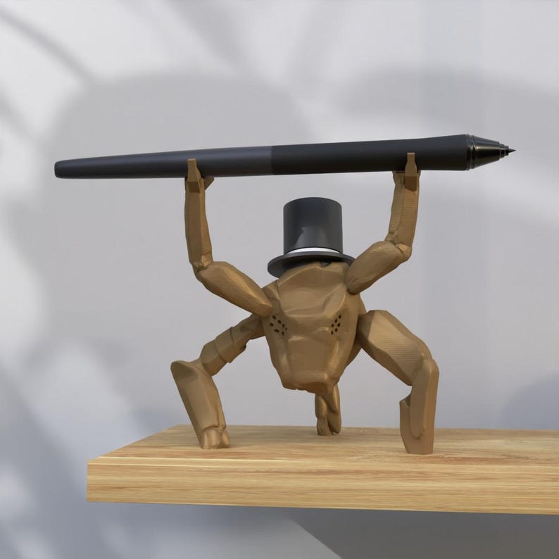 May include: A brown, stylized insect-like sculpture wearing a top hat, holding a black pen aloft. The sculpture is on a wooden shelf. The pen is approximately 12 inches long.