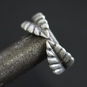 May include: A silver ring with a leaf design. The ring is made of two leaves that are intertwined.