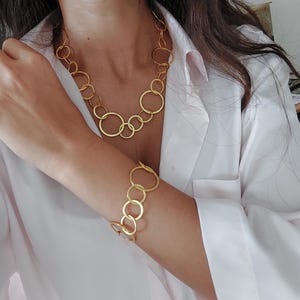 May include: A gold necklace and bracelet made of interlocking circles.