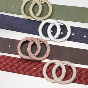 May include: Four different leather belts with a double circle buckle. The buckles are silver, gold, copper, and a hammered silver finish. The belts are in various colours, including red, brown, navy, and green.