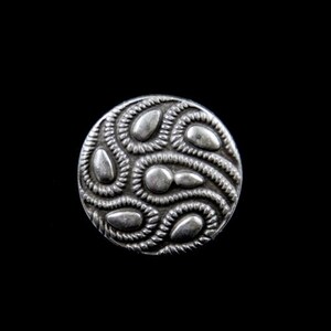 Pode incluir: Um botão de prata com um design decorativo de linhas e ovais em espiral.
