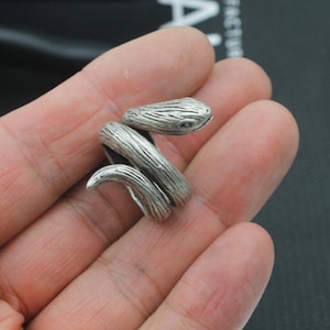 May include: A silver snake ring with a detailed textured design. The snake is coiled and the head is raised.