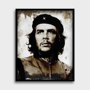 May include: Sepia-toned portrait of a man wearing a black beret with a star emblem. The image is framed in a black border, with a vintage, textured background. The subject has dark hair and a mustache.
