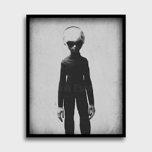 May include: Black and white photograph of a figure with a large head and large eyes, wearing a dark suit. The figure is standing in front of a textured background.