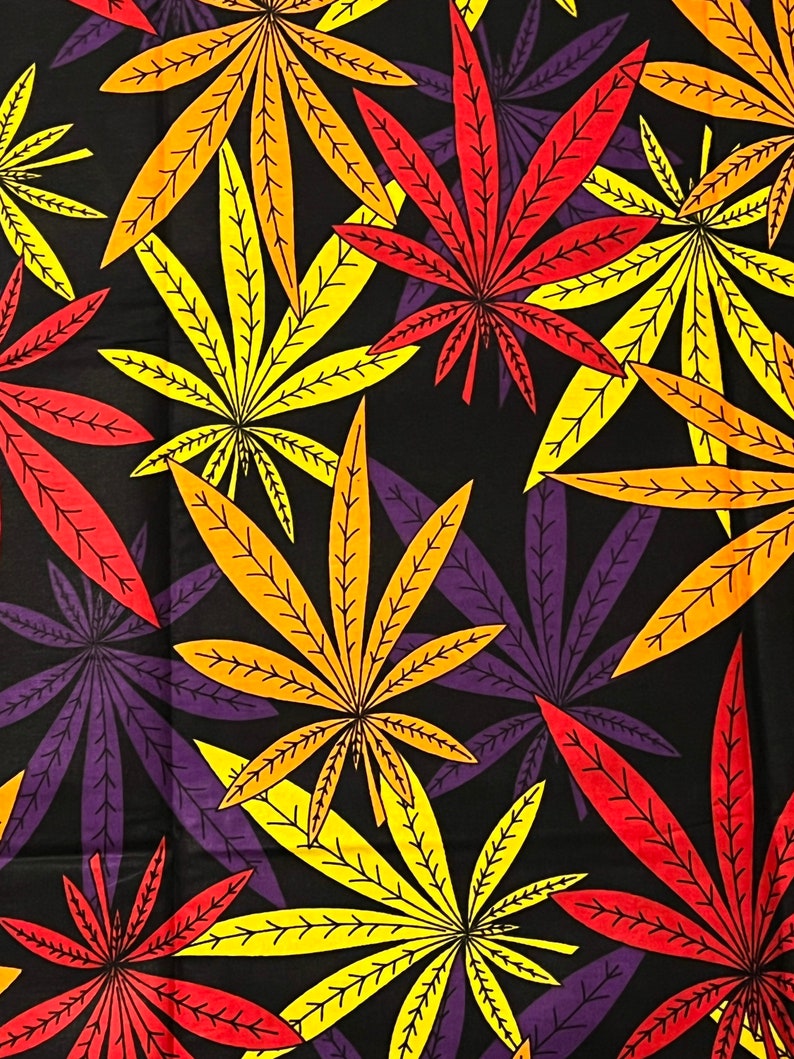 Op de afbeelding: Een zwarte achtergrond met een herhalend patroon van kleurrijke marihuanabladeren. De bladeren zijn in tinten rood, oranje, geel en paars.