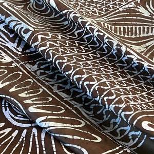 Puede incluir: Tela marr&oacute;n con un patr&oacute;n batik blanco. El patr&oacute;n presenta una variedad de formas geom&eacute;tricas, incluyendo c&iacute;rculos, cuadrados y tri&aacute;ngulos.
