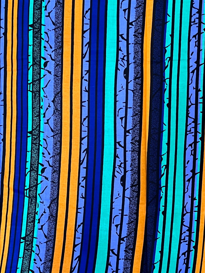 Puede incluir: Una tela colorida con rayas verticales en tonos de azul, naranja y turquesa. Las rayas est&aacute;n adornadas con un dise&ntilde;o en negro, blanco y gris.