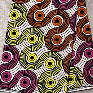 May include: White fabric with a repeating pattern of yellow, orange, pink, and black circles and lines. The fabric has the text "W6031008" printed on it.