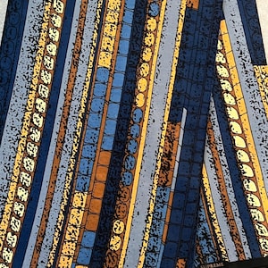 May include: A blue, yellow and brown patterned fabric with the word "SUPREME" printed on the bottom right corner.